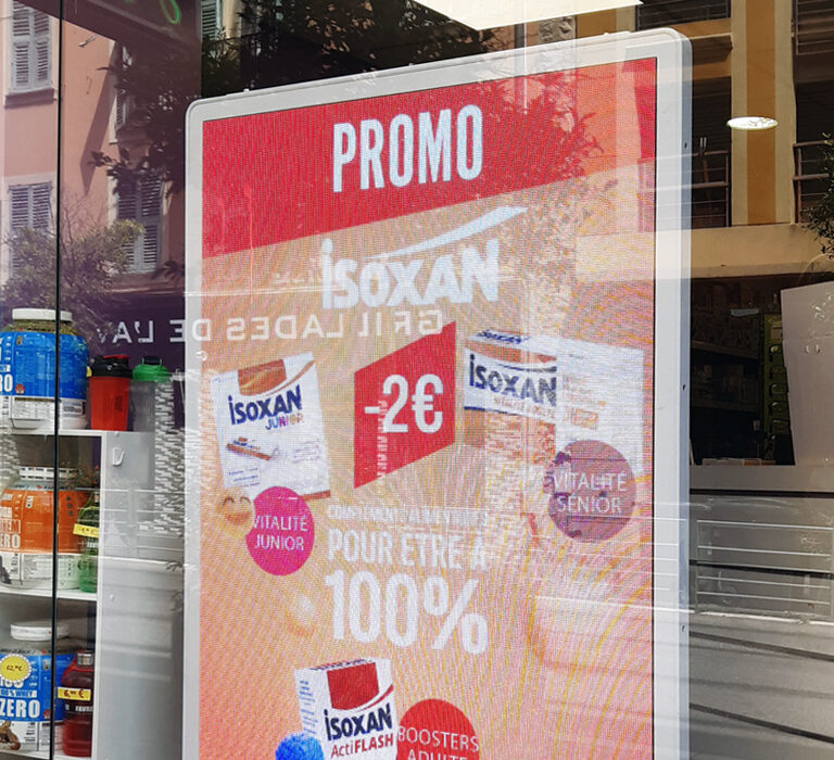 Photo de vitrine de pharmacie avec écran publicitaire vidéo Isoxan.