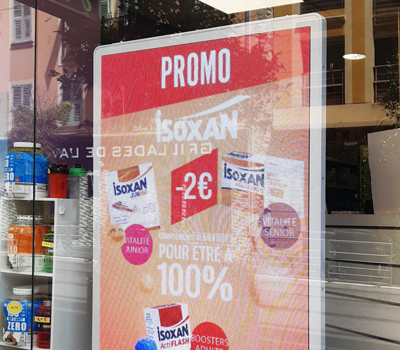 Photo de vitrine de pharmacie avec écran publicitaire vidéo Isoxan.